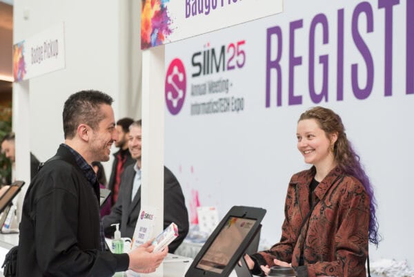 Innovative healthcare professionals engaging at the SIIM 25 Annual Meeting registration desk during the SIIM Annual Meeting, a leading event for medical imaging and informatics experts.