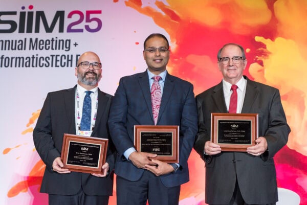 Award ceremony at SIIM Annual Meeting recognizing excellence in imaging informatics and informaticsTECH. Attendees are holding plaques and dressed in professional business attire.