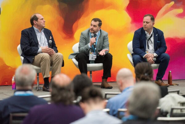 Panel discussion at SIIM Annual Meeting about medical imaging innovation and AI integration in radiology workflows in front of vibrant orange background.