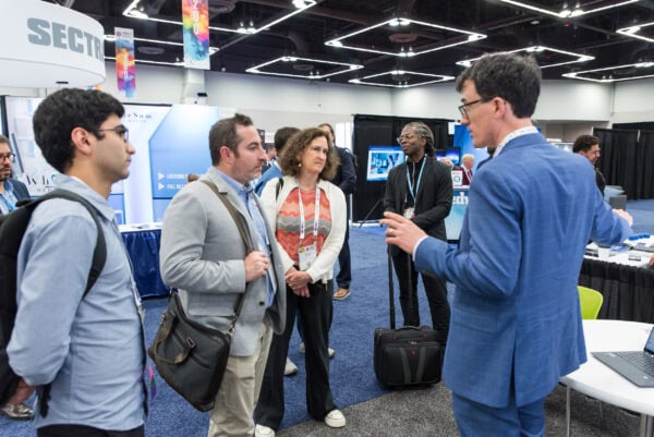 Modern conference scene at SIIM Annual Meeting, attendees engaging in discussions about medical imaging and healthcare technology innovations.