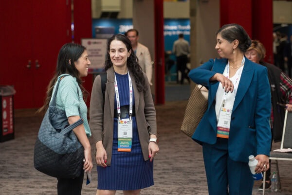 Elegant group of diverse medical professionals networking at SIIM Annual Meeting, engaging in a lively conversation, showcasing collaboration and innovation in medical imaging and radiology.