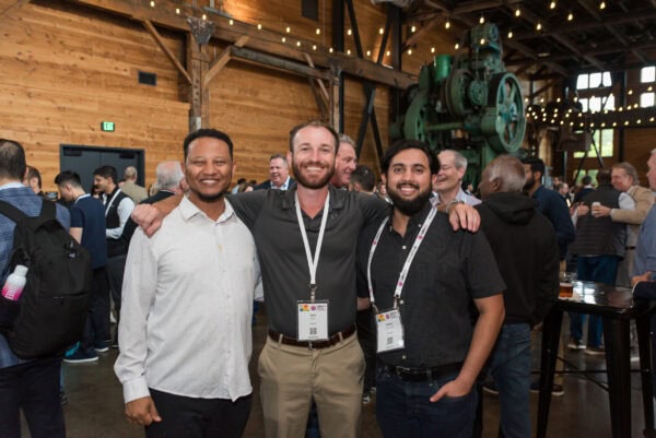 Smiling conference attendees networking at SIIM Annual Meeting in a rustic wooden venue with industrial decor and lighting, engaging in radiology and medical imaging discussions for healthcare innovation.