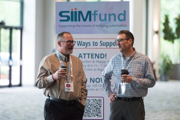 Engaged professionals networking at SIIM Annual Meeting discussing imaging informatics and innovative healthcare solutions.