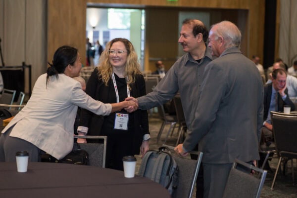 People networking and shaking hands at the SIIM Annual Meeting, a prominent event in medical imaging and informatics conferences.