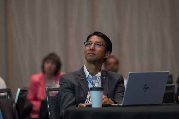 Highly engaged professional attending the SIIM Annual Meeting, focusing on radiology and medical imaging innovations, seated with a laptop and conference badge, showcasing active participation in industry discussions.