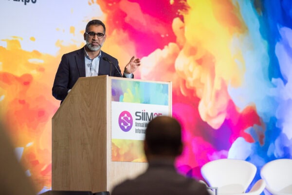 Innovative speaker at SIIM Annual Meeting delivering a presentation on imaging informatics and AI in healthcare, with colorful abstract background and audience engagement.
