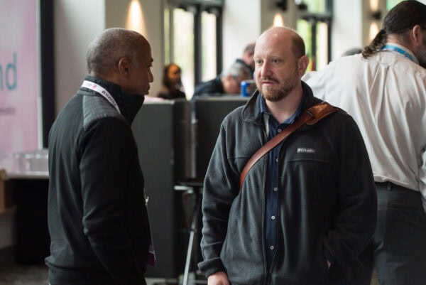 Black man and bald man engaging in conversation at SIIM Annual Meeting, medical imaging conference, healthcare professionals networking, radiology innovation, medical imaging technology, medical event, corporate discussion, professional networking, radiology professionals, SIIM Annual Meeting 2023.