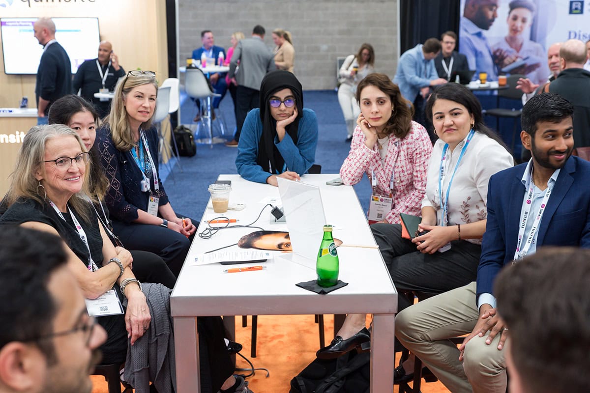 people sitting around a table listening to a speaker