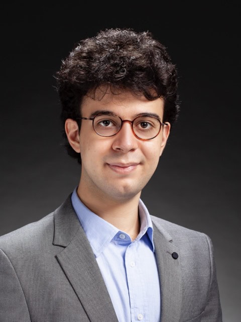 Young professional with glasses and dark curly hair attending the SIIM Annual Meeting, showcasing medical imaging and informatics innovations.