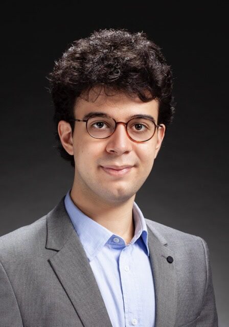 Young professional with glasses and dark curly hair attending the SIIM Annual Meeting, showcasing medical imaging and informatics innovations.