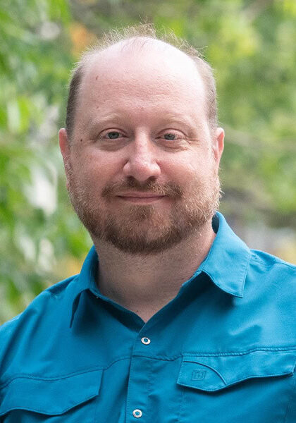 A man with a beard and blue shirt attending the SIIM Annual Meeting outdoors, engaging with healthcare professionals and showcasing medical imaging technology.