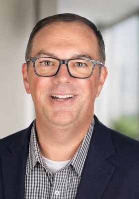 Professional portrait of a male speaker at the SIIM Annual Meeting, showcasing a confident and engaging presentation style in a modern conference setting.