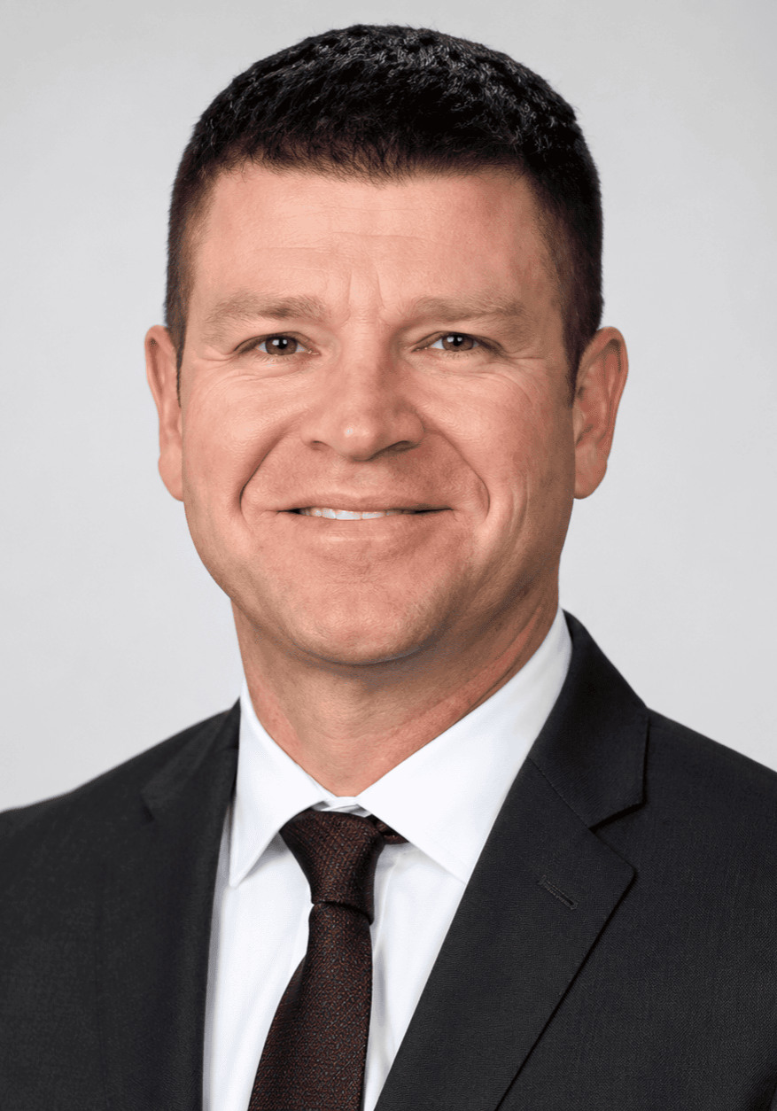 A confident male medical professional in a suit speaking at the SIIM Annual Meeting, engaging with healthcare and imaging technology professionals.