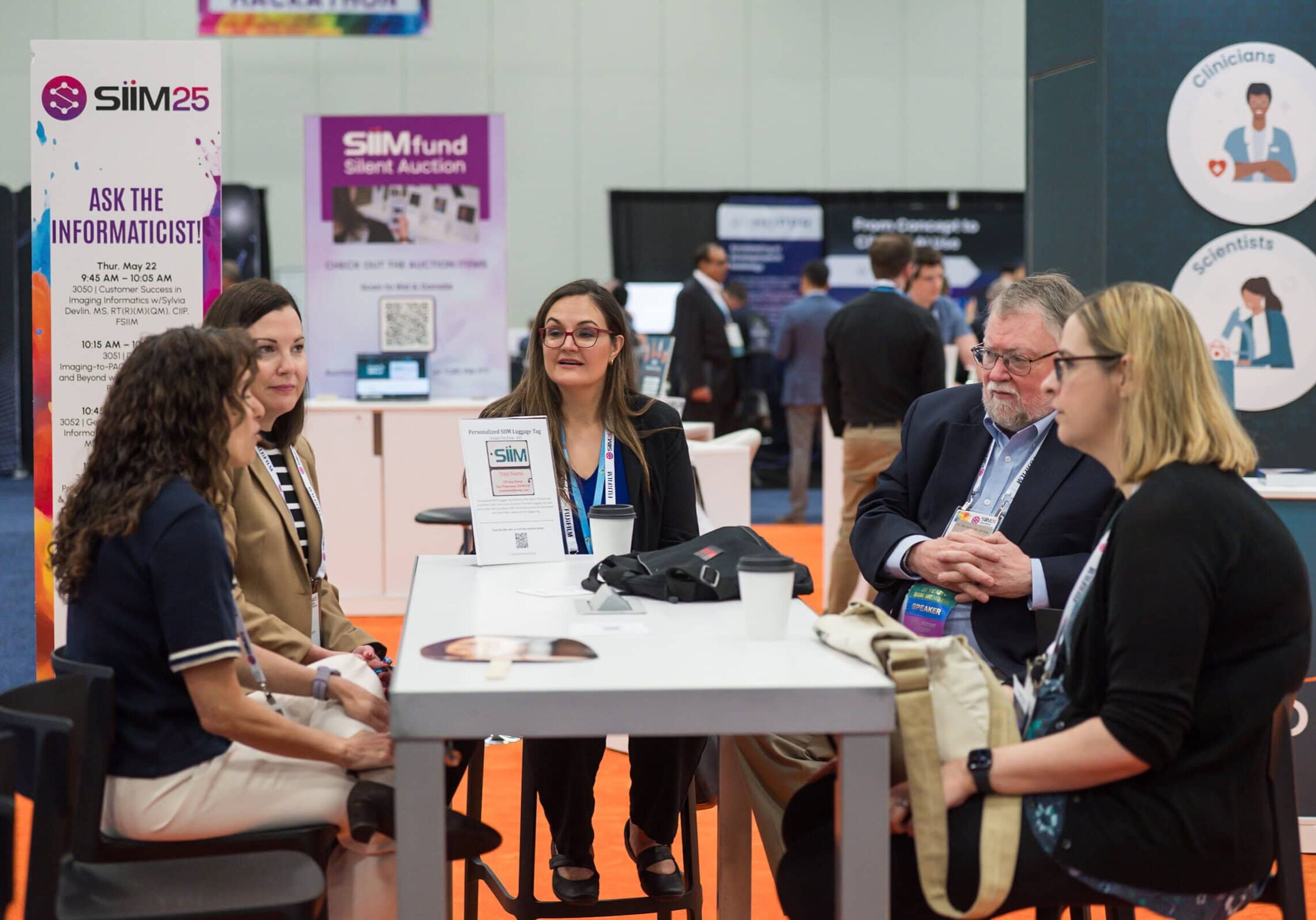 Healthcare professionals engaging in a discussion at the SIIM Annual Meeting, focusing on innovative imaging informatics and learning beyond the booth.