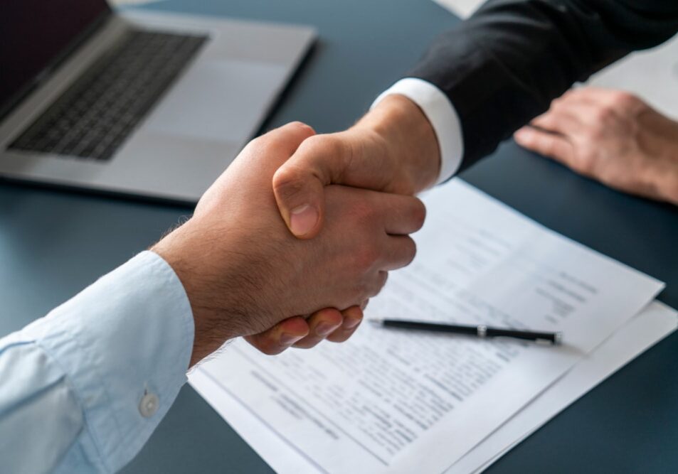 Close,Up,Of,Two,Businessmen,Shaking,Hands,In,Blurred,Office